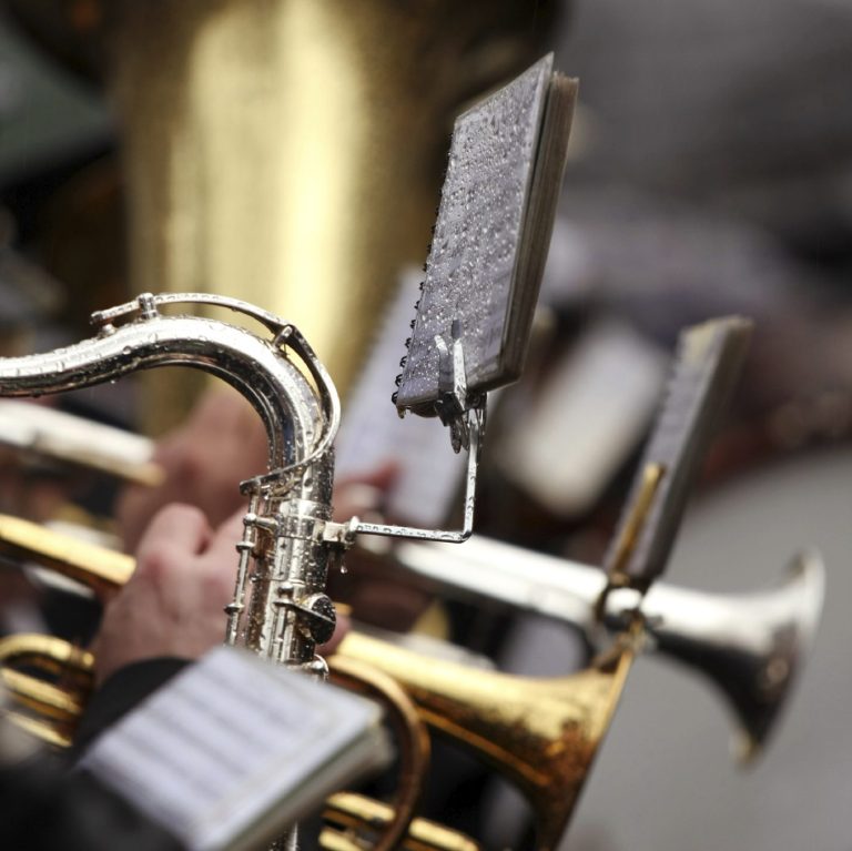 People playing brass instruments outside in the rain